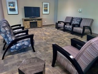 A comfortable waiting room featuring a variety of chairs and a television.