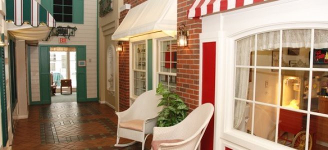A cozy indoor setting with two chairs next to brick walls and windows, adorned with an awning and greenery.