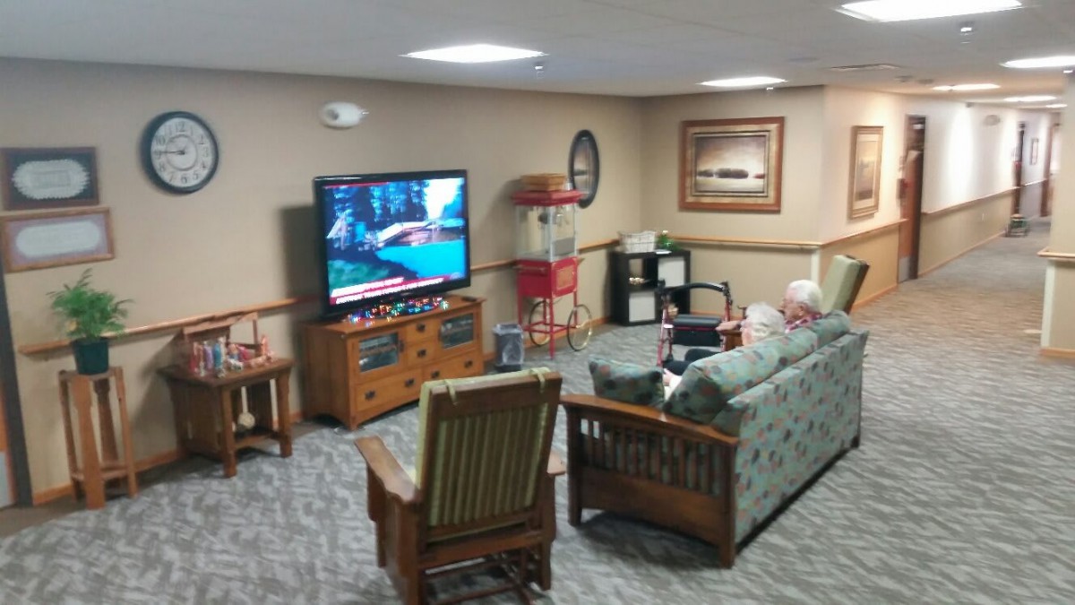 A cozy living room setup with a large TV, seating area, and a popcorn machine in the corner.