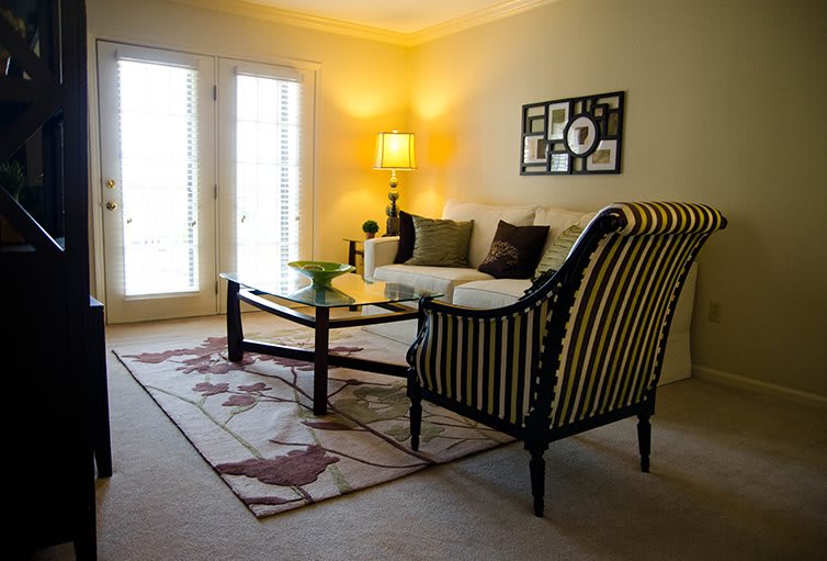 A cozy living room with modern decor, featuring a sofa, armchair, coffee table, and stylish lighting.