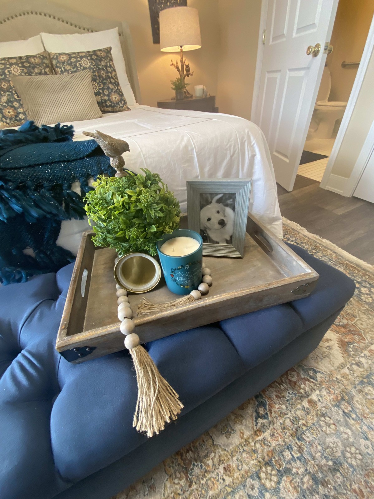 A cozy bedroom setup featuring a decorative tray with a plant, candle, and photo frame.