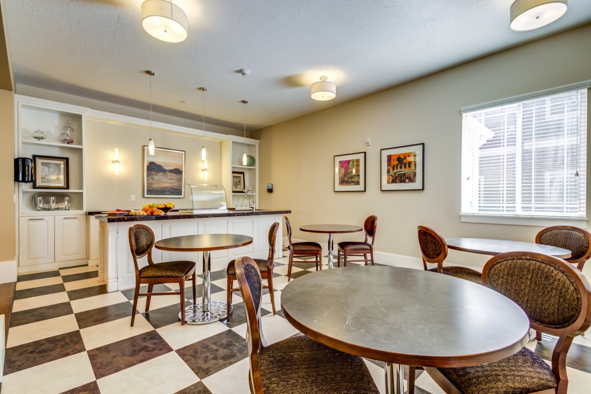 A cozy cafe interior with round tables, wooden chairs, and a checkered floor.