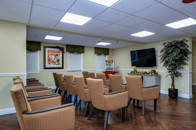 A well-arranged conference room with rows of chairs facing a large television and artwork on the wall.