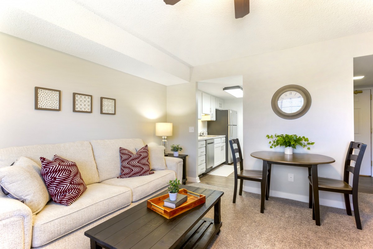 A cozy living room with a sofa, coffee table, and adjoining dining area.