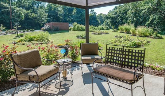 A cozy patio setup with chairs and a table overlooking a lush garden.