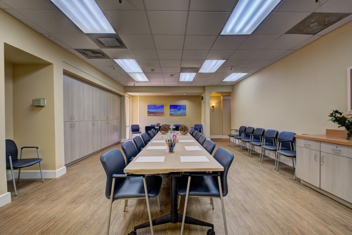 A well-lit conference room with a central table surrounded by chairs, designed for meetings and office gatherings.