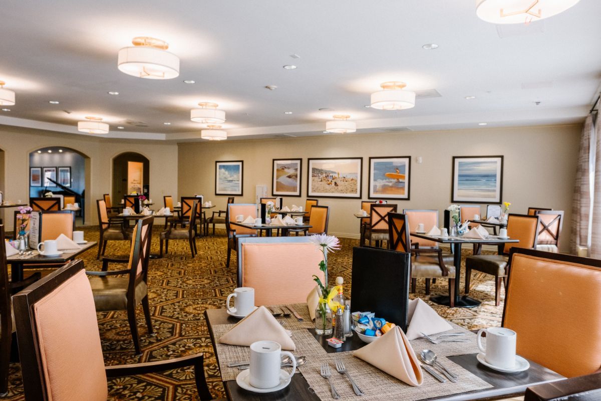 A neatly arranged dining area with tables and chairs, decorated with artwork and soft lighting.
