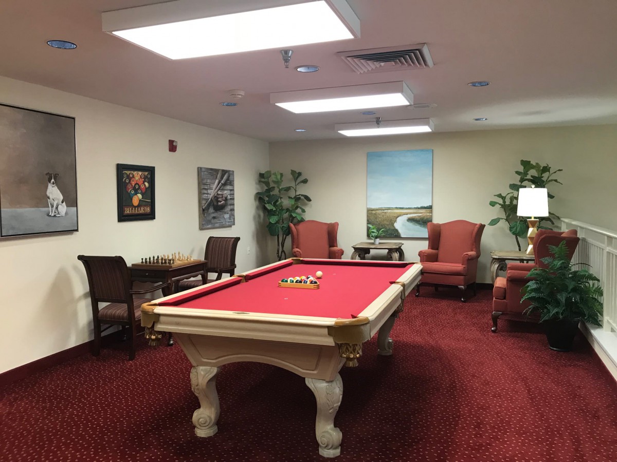 A cozy game room featuring a red pool table surrounded by comfortable seating and artwork.