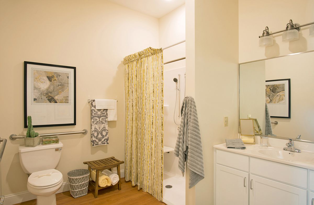 A well-lit bathroom with a shower area, decorative towels, and a neatly organized sink space.