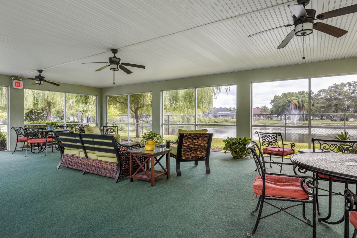 A cozy screened porch with outdoor furniture overlooking a lake.