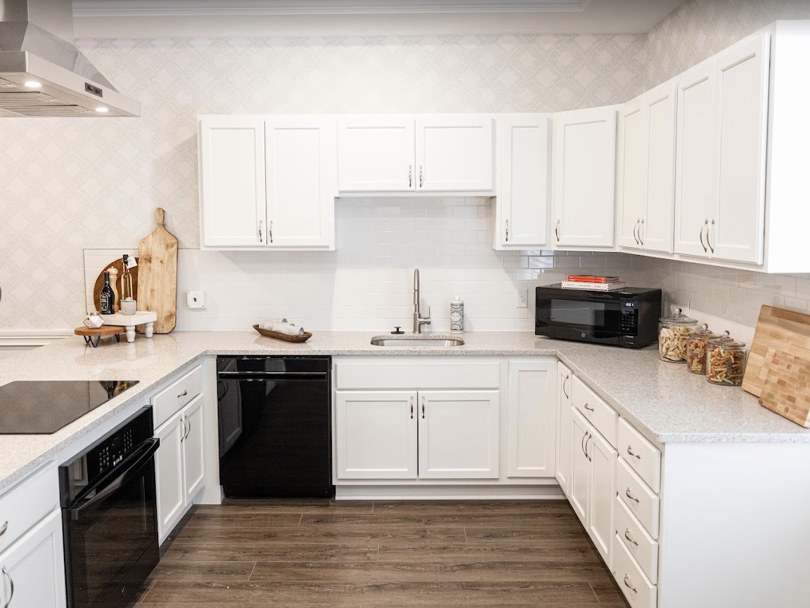 A modern kitchen with white cabinets and dark appliances.