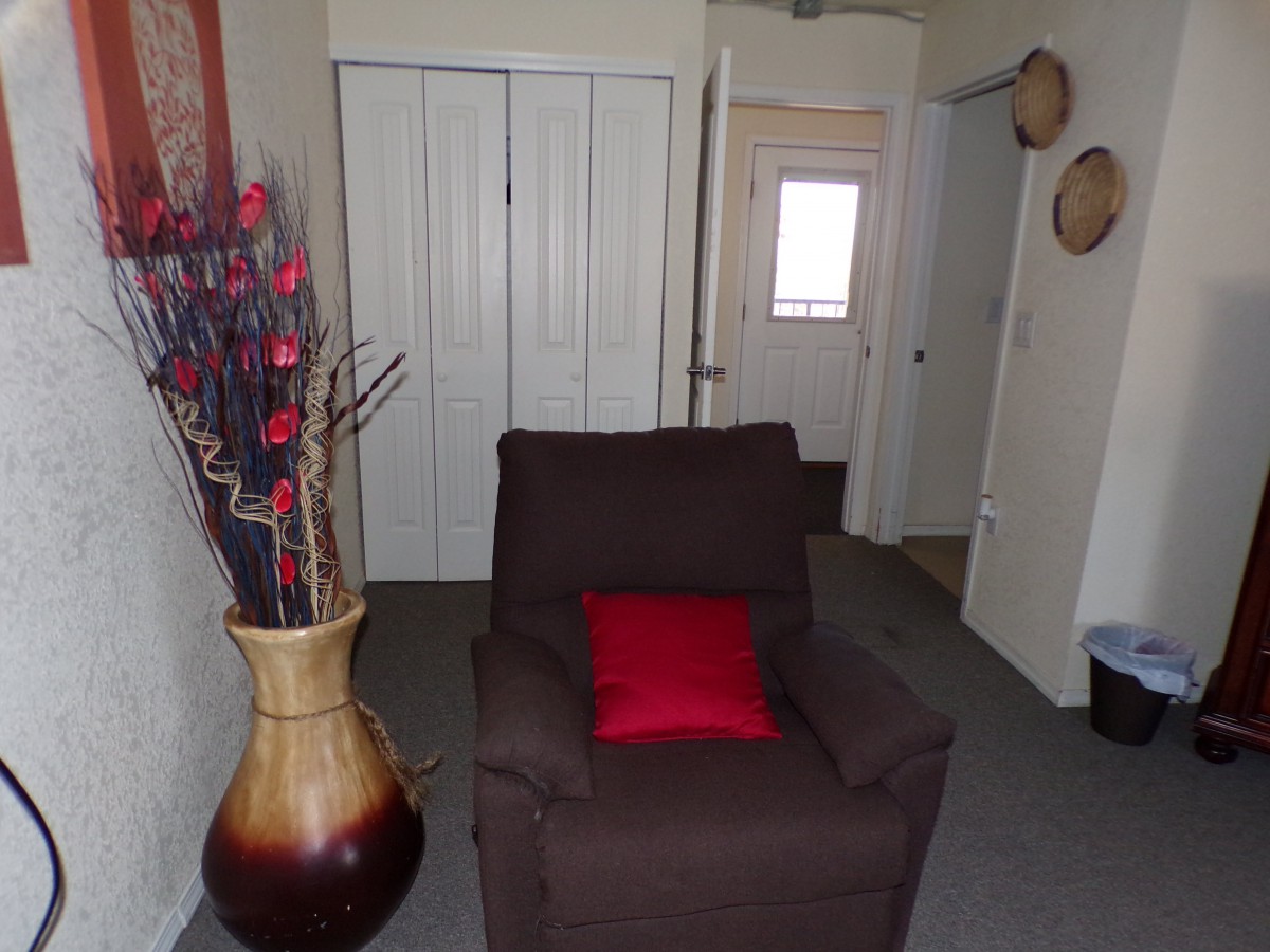 A cozy living room with a brown chair, a red pillow, and decorative elements.