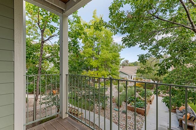 A scenic view from a balcony overlooking a lush garden and trees.