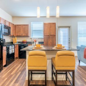 A modern kitchen with wooden cabinets, an island, and stylish bar stools.