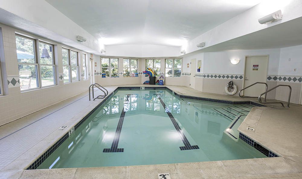 An indoor swimming pool with clear water and surrounding windows.