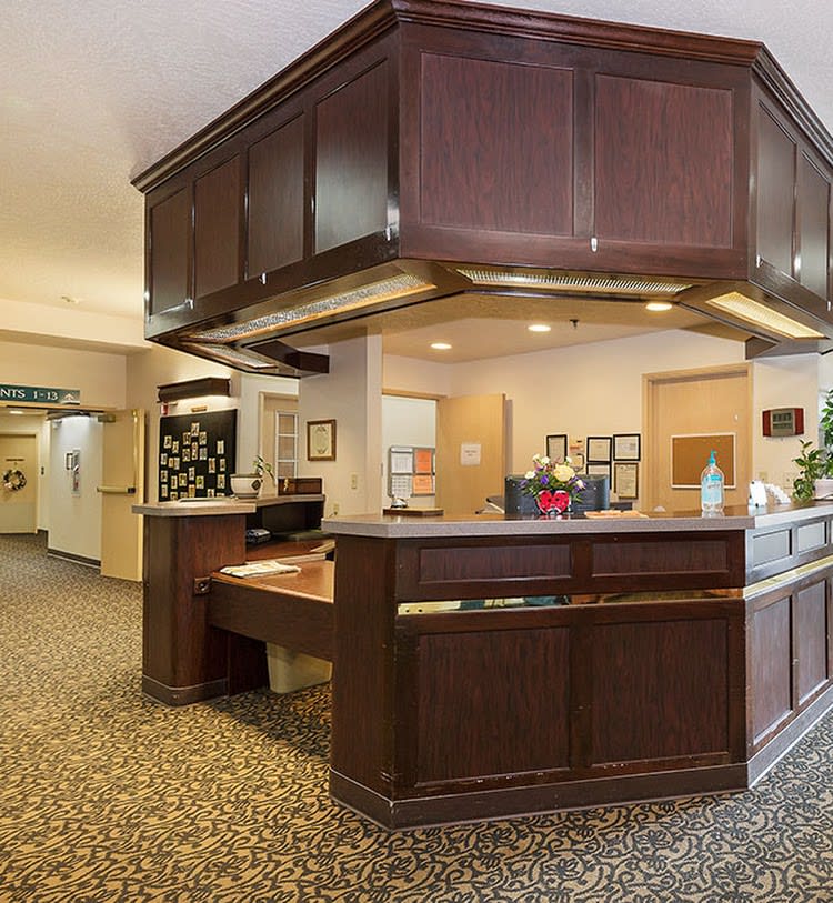 A hotel lobby with a wooden reception desk and carpeted floors.