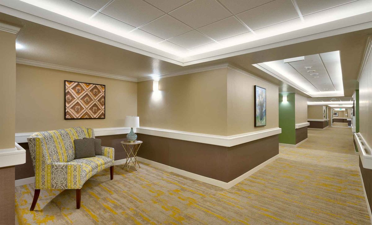 A modern hallway with stylish lighting, artwork, and comfortable seating.