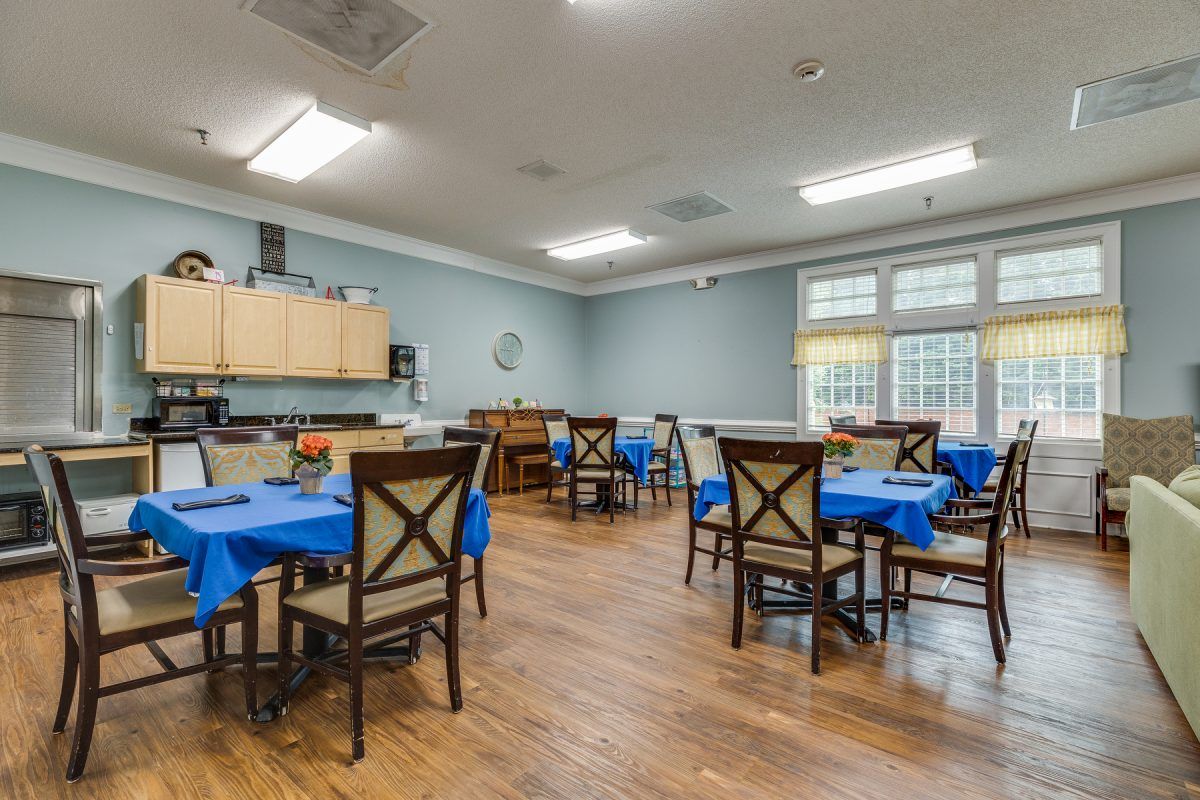A well-lit dining room with multiple tables and blue tablecloths.