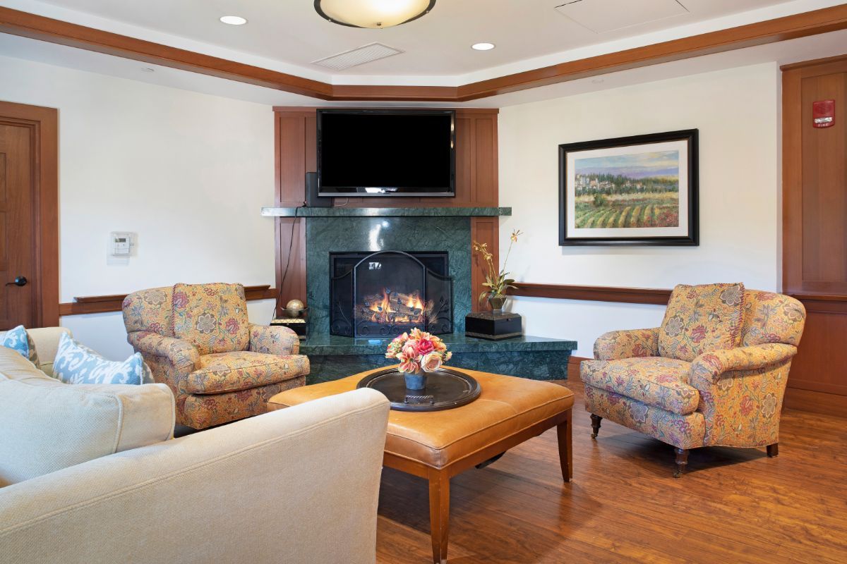 A cozy living room with a fireplace, comfortable seating, and a mounted television.