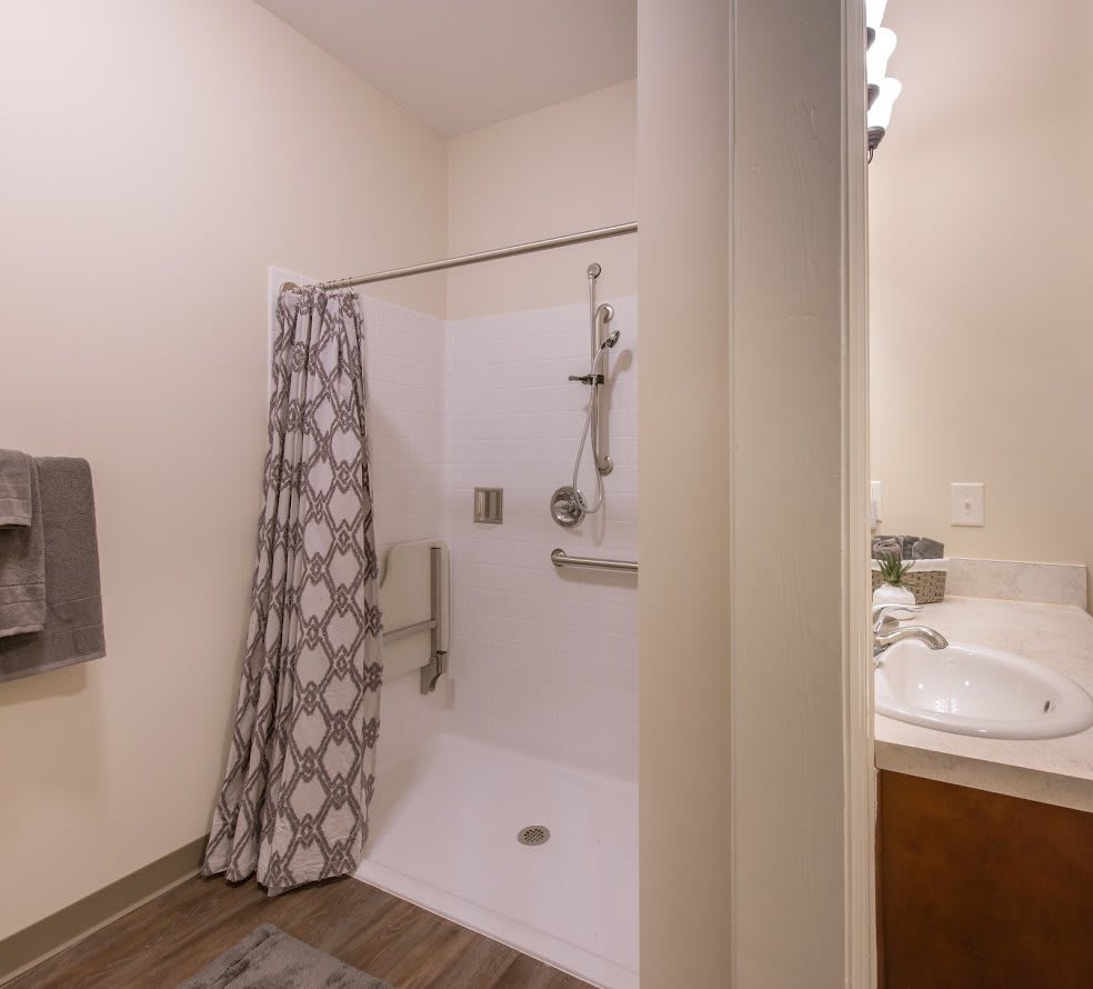 A modern bathroom featuring a shower with a geometric-patterned curtain, a sink, and a mirror.