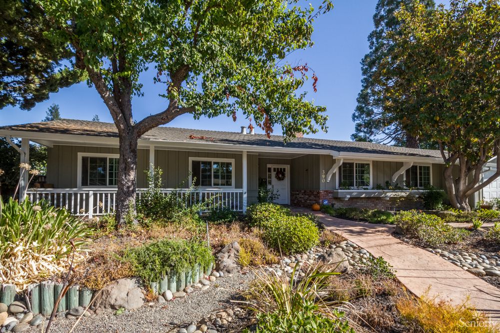 A single-story house with a landscaped front yard featuring a pathway and trees.