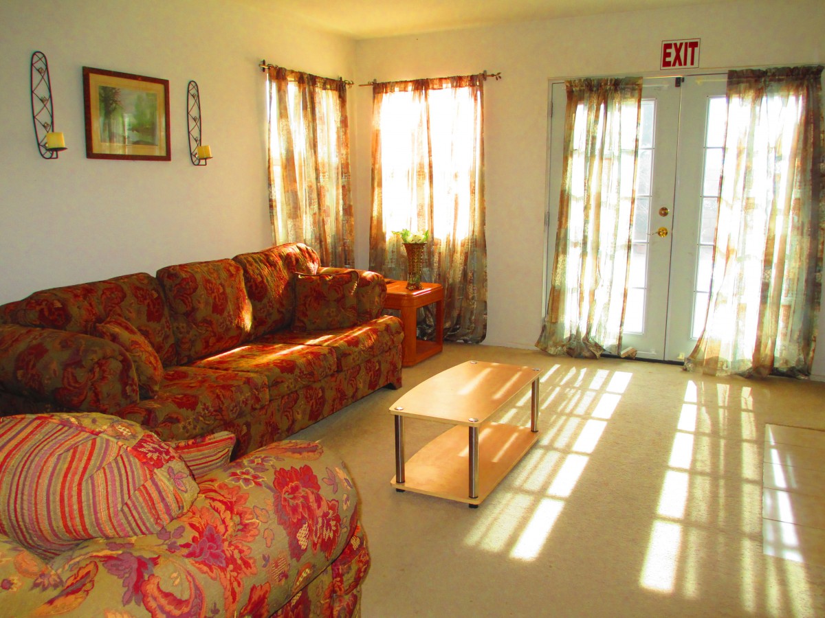 A cozy living room bathed in warm sunlight, featuring a floral sofa and a simple coffee table.