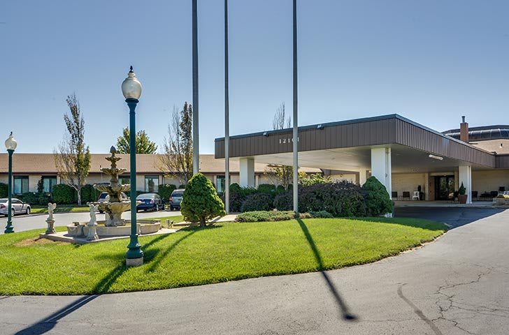 Entrance of a hotel with well-maintained landscaping and flagpoles.