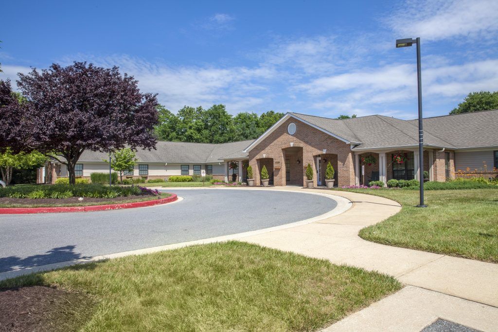A suburban building with a circular driveway and landscaped surroundings.