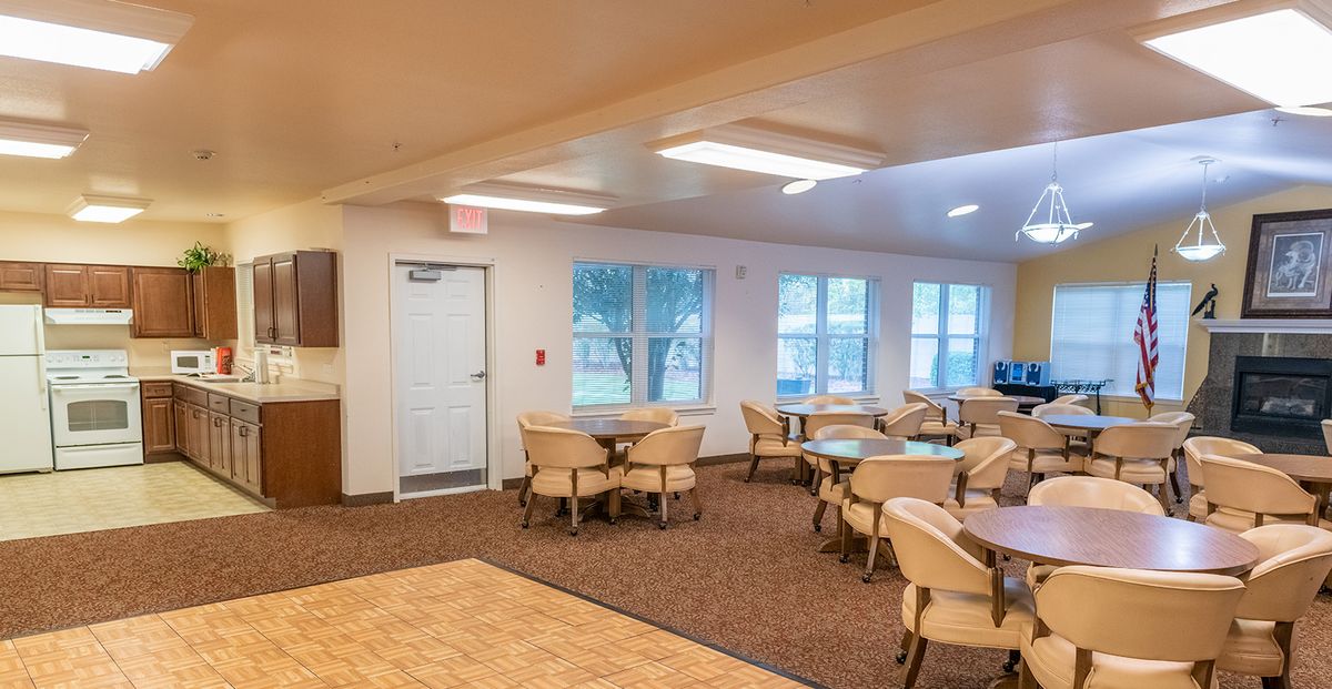 A spacious dining area with multiple tables and chairs, featuring large windows and comfortable lighting.