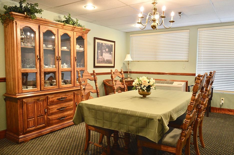 A cozy dining room with a wooden table, chairs, and a china cabinet under a chandelier.