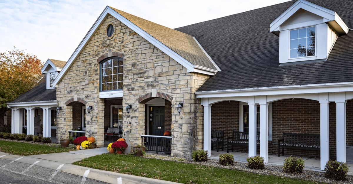 A stone facade building with a front porch and landscaped entrance.