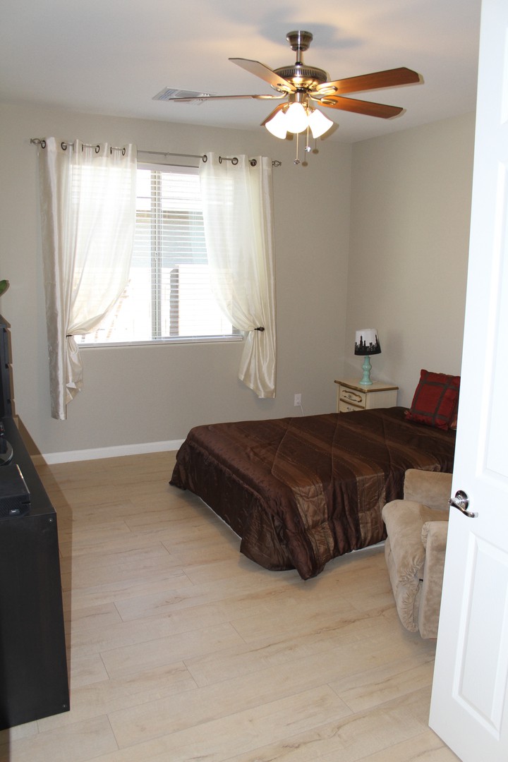 A minimalist bedroom with simple decor, featuring a bed, window with curtains, and a lamp.