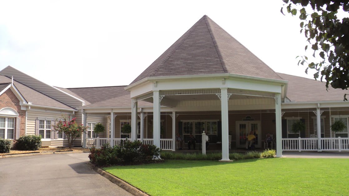 A large house with a prominent porch, surrounded by a well-maintained lawn.
