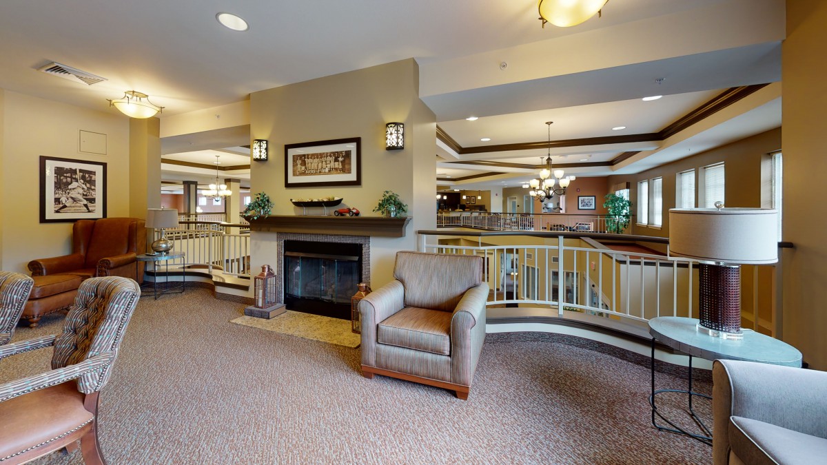A cozy living room with a fireplace and armchair, featuring warm lighting and elegant decor.