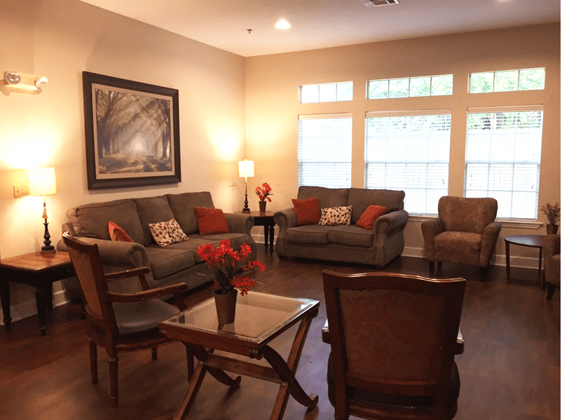 A cozy living room with sofas and armchairs arranged around a central table, warm lighting, and decorative elements.