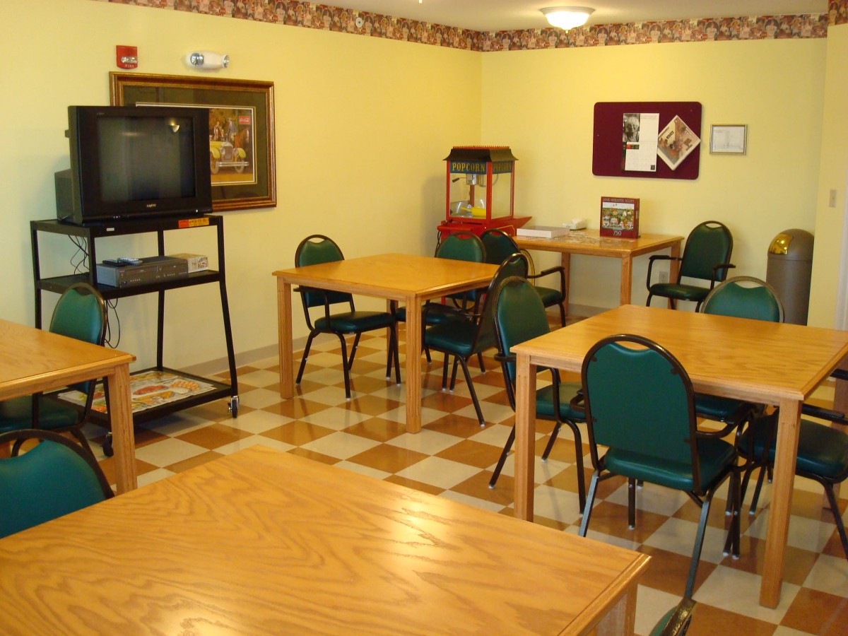 A community room with tables, chairs, a television, and a popcorn machine.
