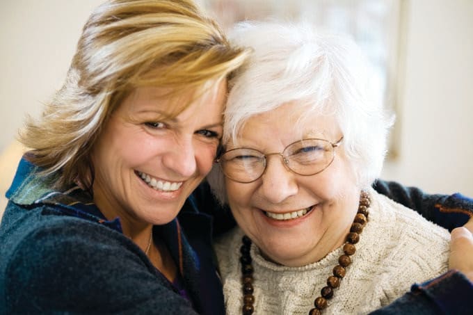 A joyful moment shared between two women, one elderly and the other younger, smiling warmly together.