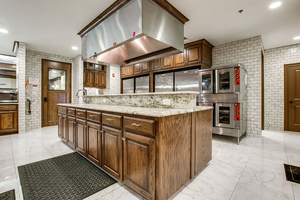 A spacious modern kitchen with wood cabinets, a large island, and stainless steel appliances.