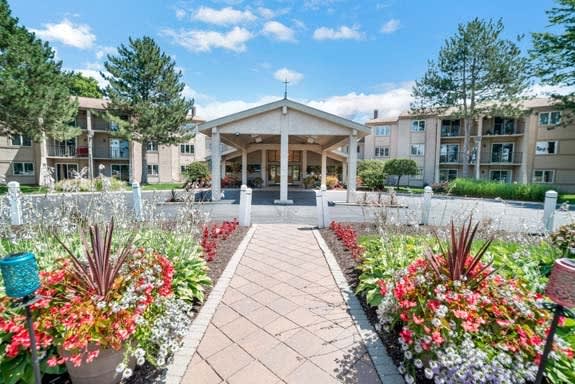 A beautifully landscaped pathway leading to a building entrance, surrounded by vibrant flowers.
