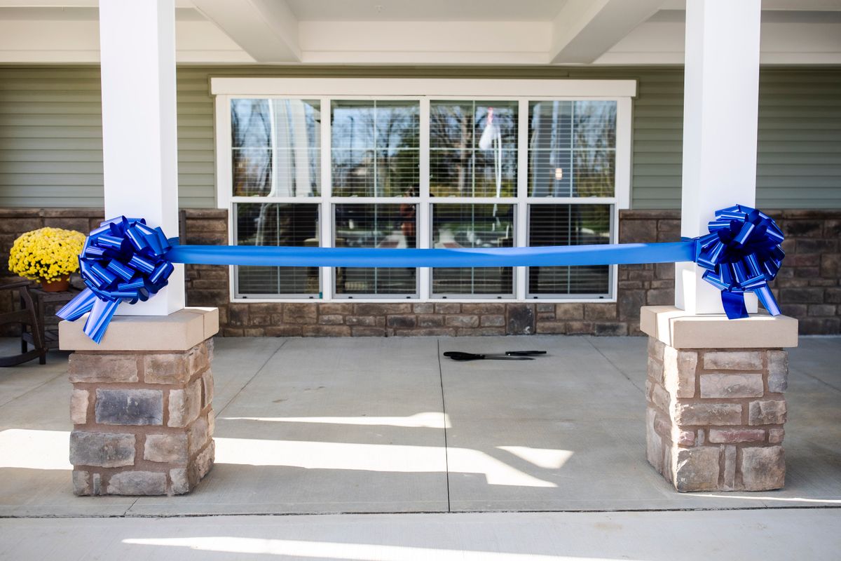 A blue ribbon stretched across a building entrance, prepared for a ribbon-cutting ceremony.