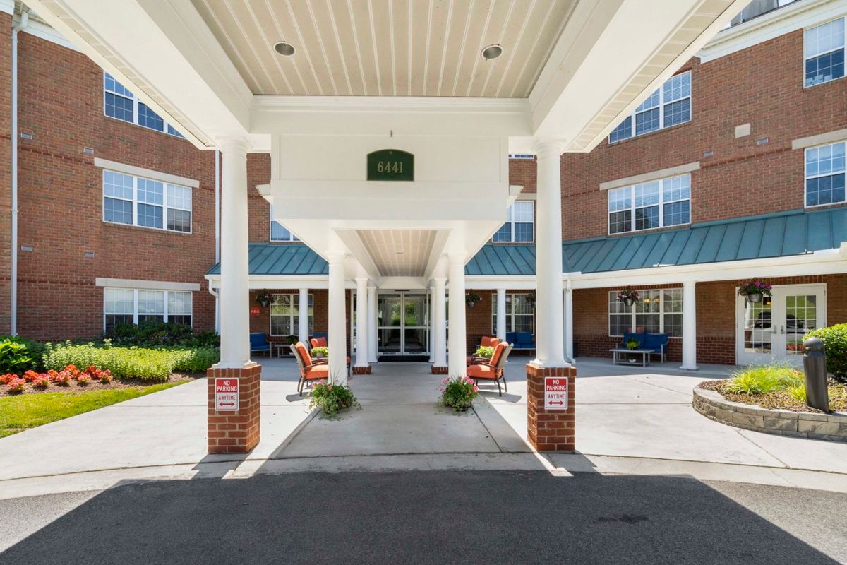 The entrance of a brick building featuring columns and a covered porch.