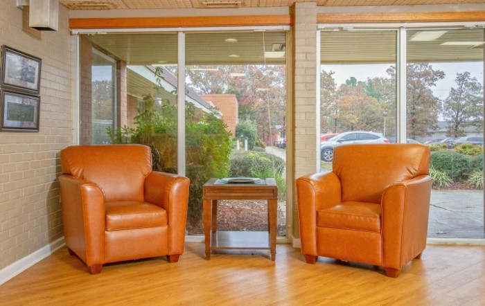 A cozy waiting area with two leather armchairs and a small table by the window.