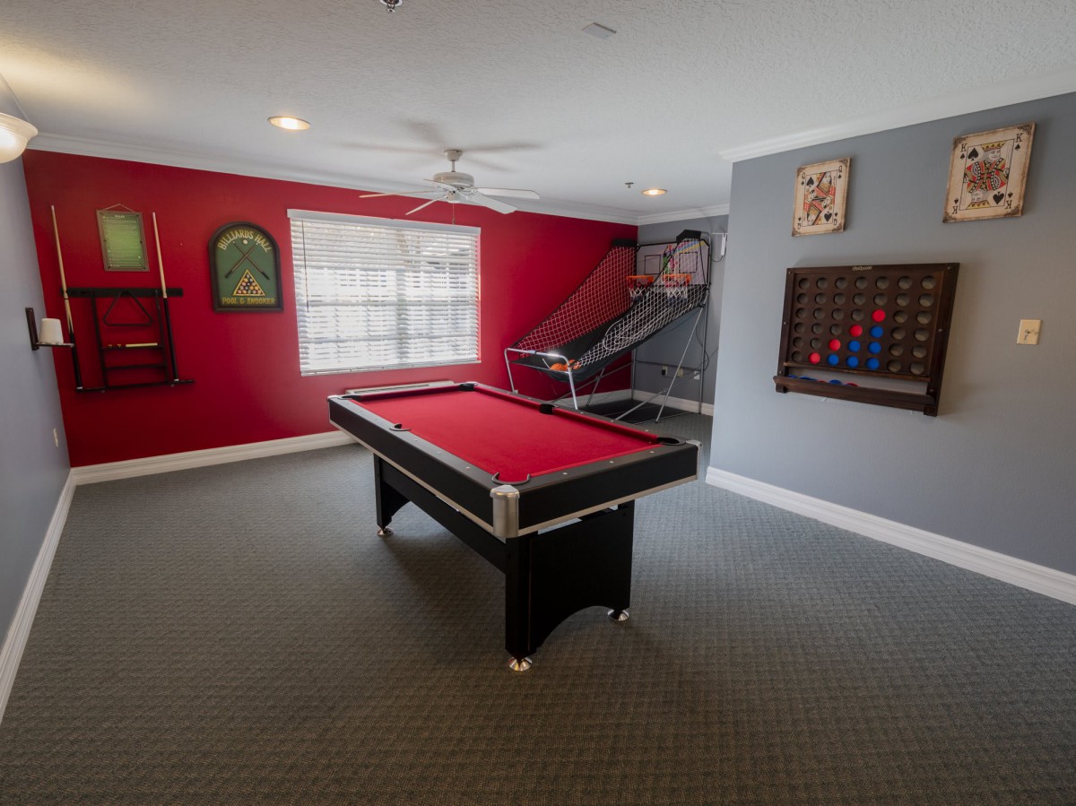 A vibrant game room with a red pool table and decorative wall art.