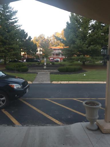 A view of a parking area with trees and a building in the background.