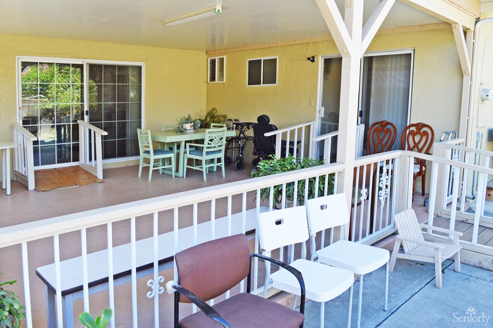 A cozy outdoor patio with a table and chairs, surrounded by a wooden railing.
