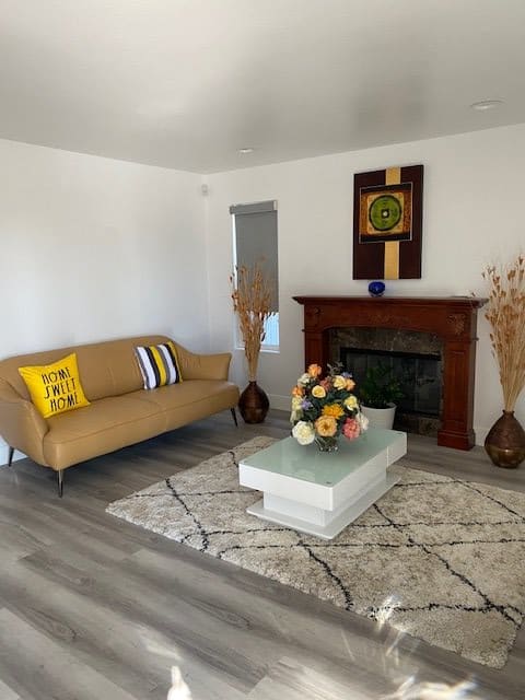 A modern living room featuring a sofa, coffee table, and fireplace adorned with decor.