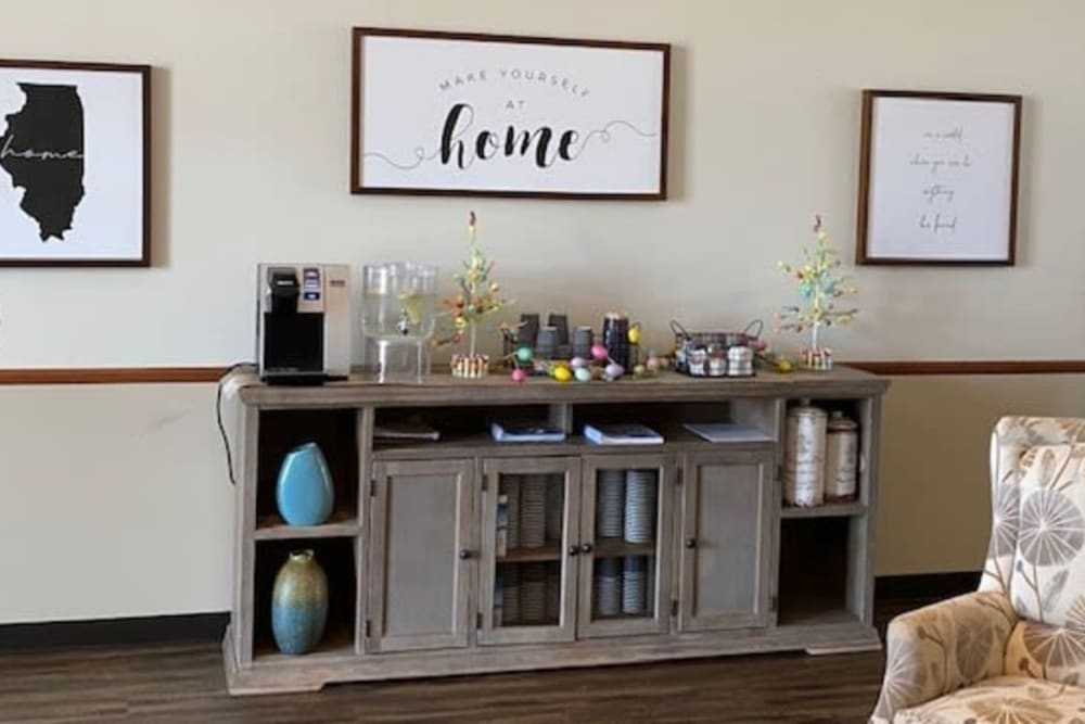 A sideboard with a coffee station setup, decorated with vases and a 'home' sign.