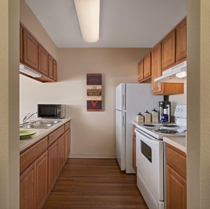 A compact kitchen in an apartment with wooden cabinets and modern appliances.