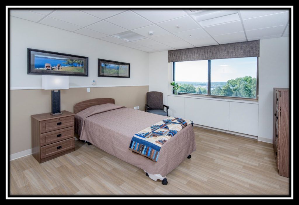 A minimalist hospital room featuring a single bed with a window offering a scenic view.