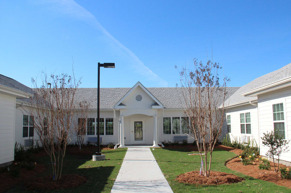 A residential building with a landscaped front yard and a walkway leading to the entrance.